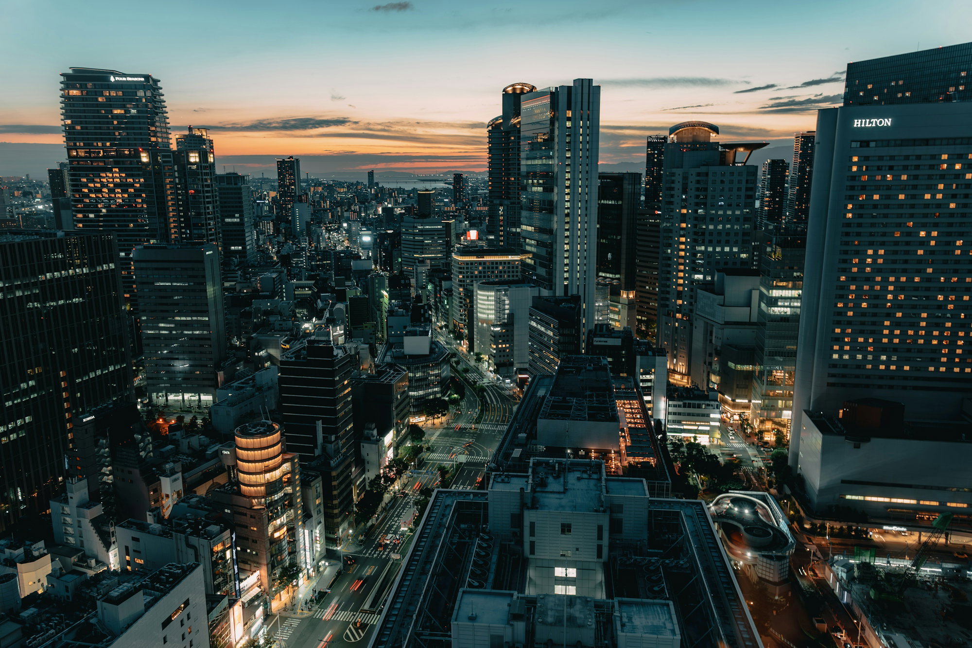 Aerial view of the Osaka skyline at night with illuminated skyscrapers and busy streets
